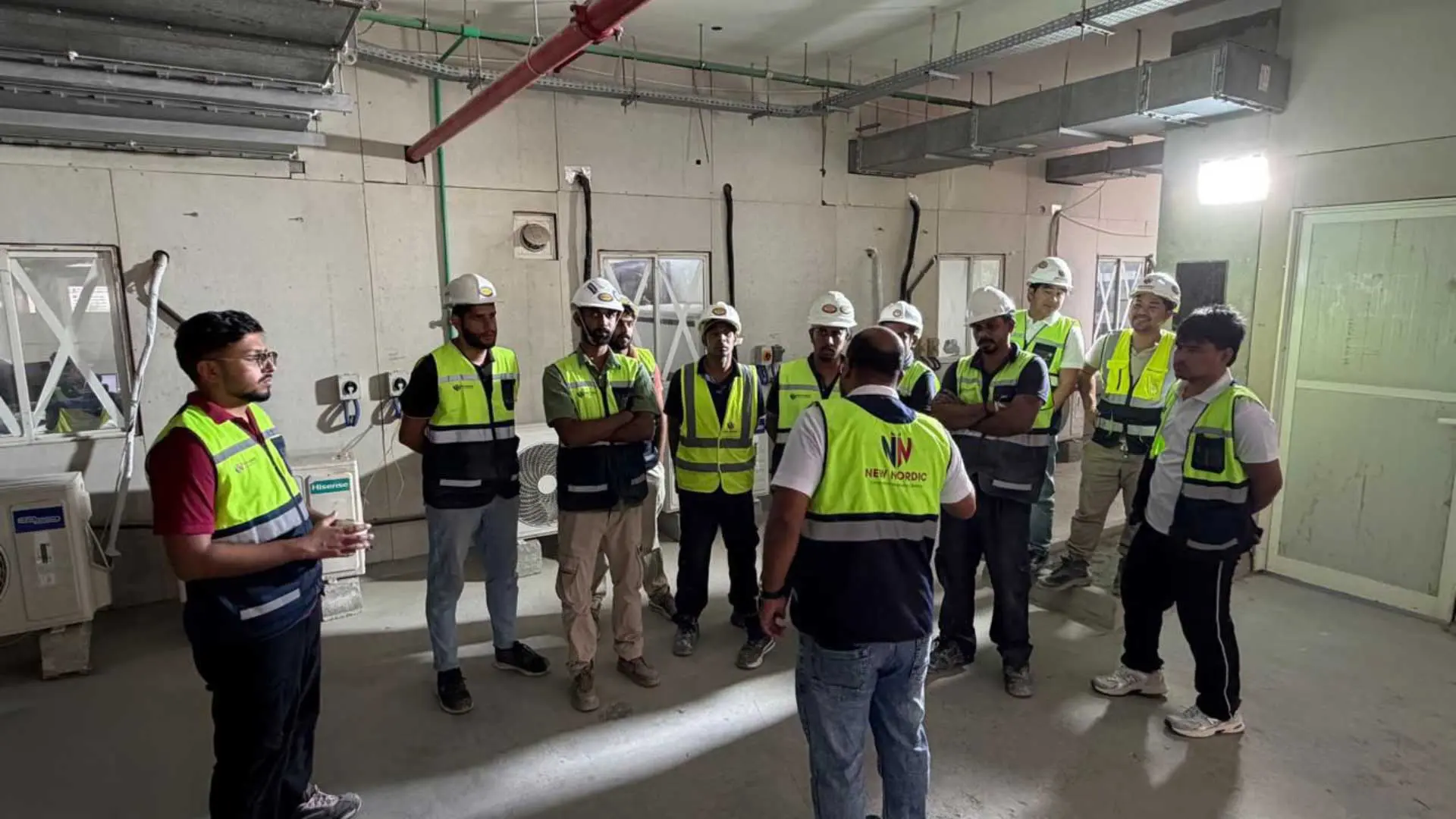 New Nordic engineers and workers gathered for a site briefing inside an unfinished building