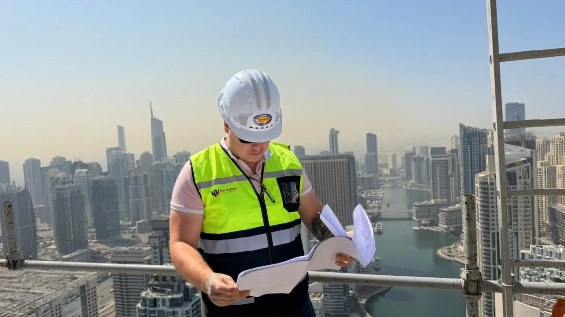 New Nordic engineer reviewing structural plans on a Dubai high-rise, city skyline behind