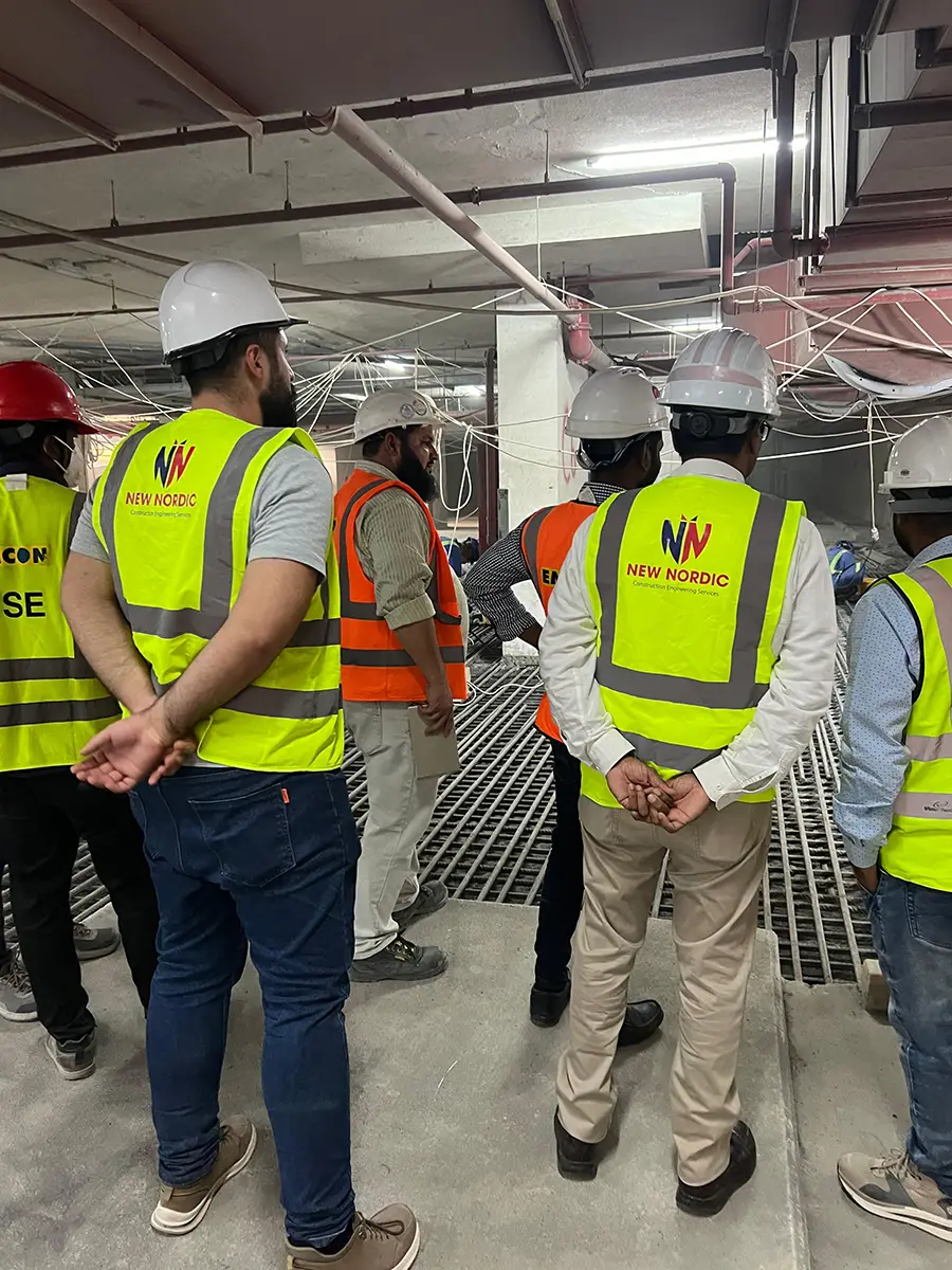 New Nordic engineers in hard hats inspecting exposed rebar flooring inside an unfinished building