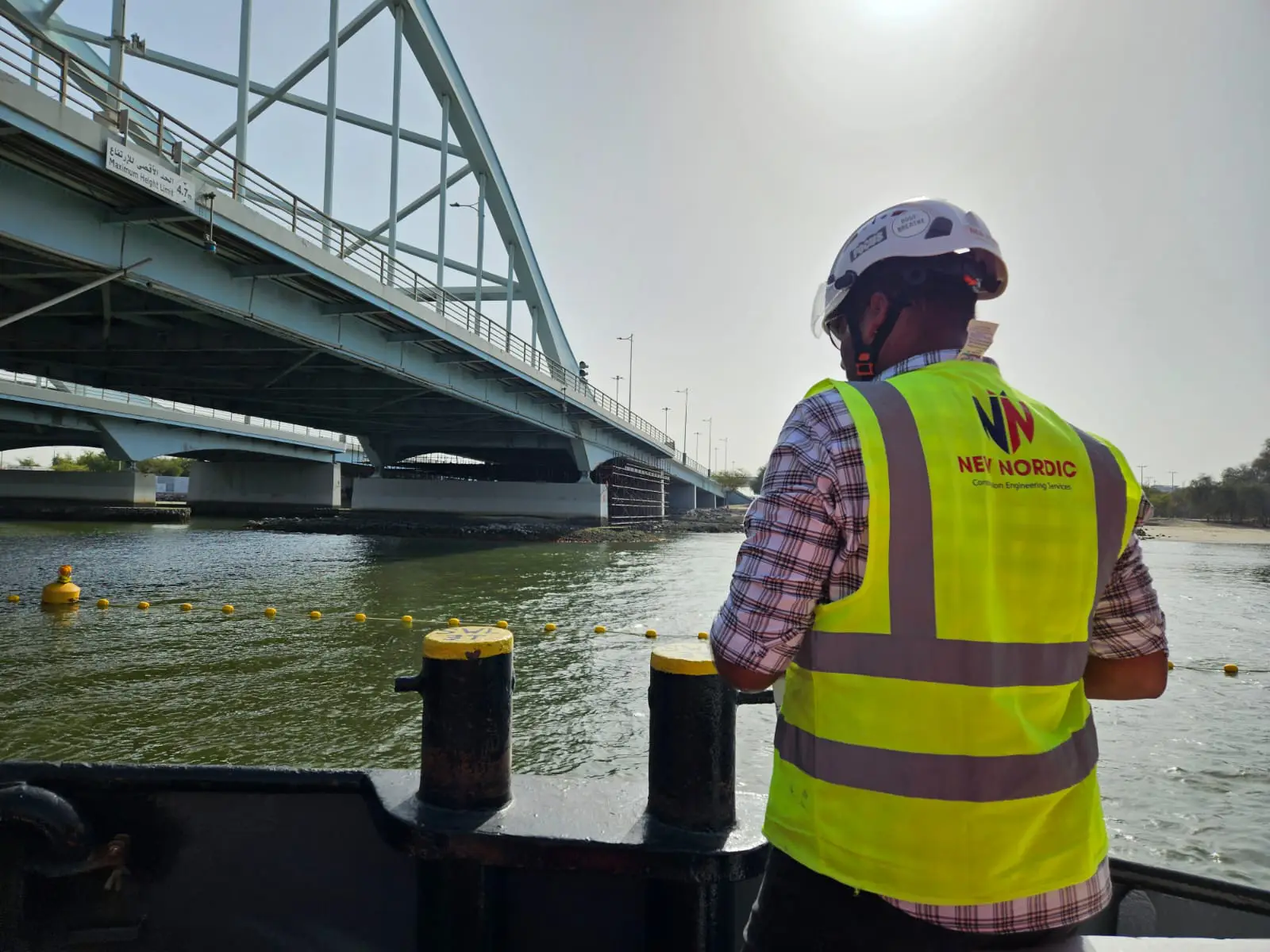 New Nordic engineer aboard a boat observing an arch bridge over a waterway during a structural inspection
