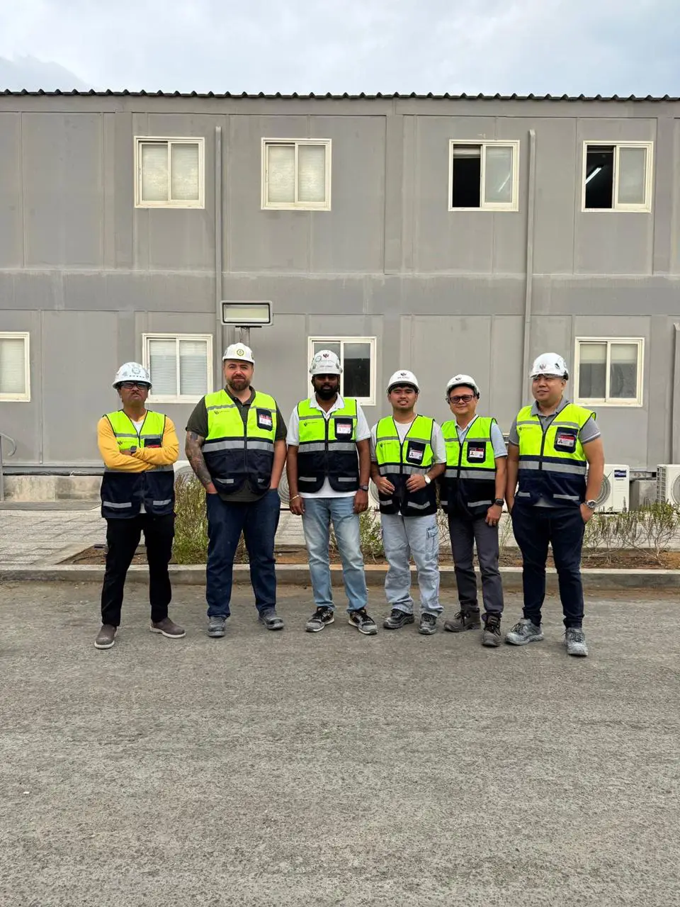 Team of New Nordic engineers in hard hats and safety vests outside a site office in the UAE